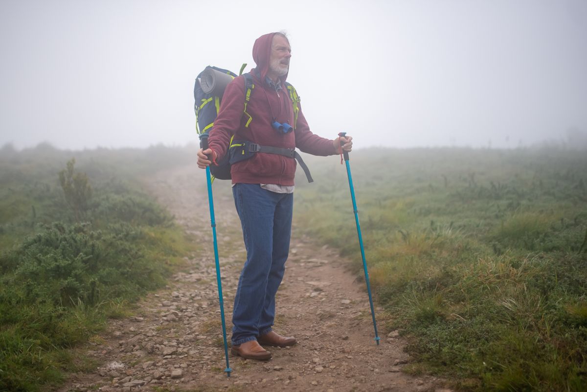 An older traveler hiking outdoors in cold-weather gear